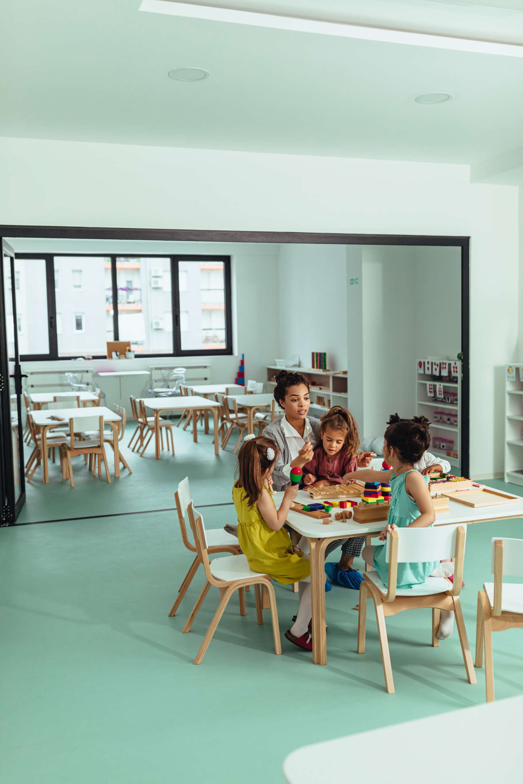 Teacher is playing with cheerful children at kindergarten