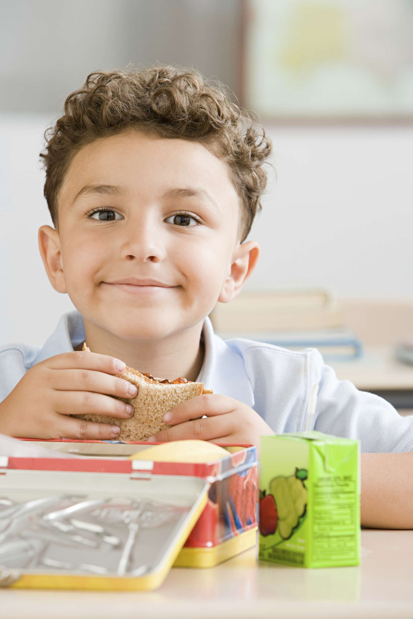 Young boy enjoying his lunch at school with a bright smile